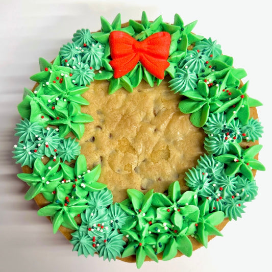 Cookie with green icing wreath and red bow on a white background